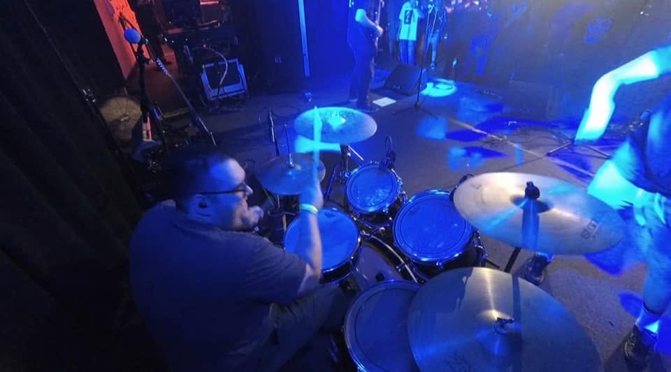 Overhead view of Peter Rodriguez playing drums under blue stage lights